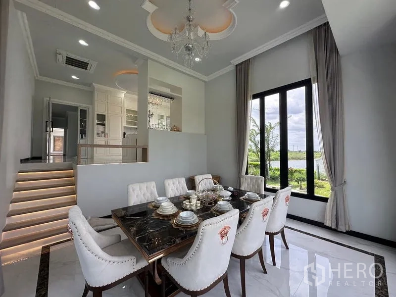 Detached House for sale in Sai Noi, Nonthaburi - Elegant dining room with chandelier, tall windows and garden-lake outlook.