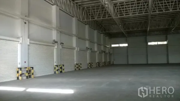 Warehouse for rent in Bang Sao Thong, Samut Prakan - Spacious warehouse interior with steel truss roof and shutter doors.