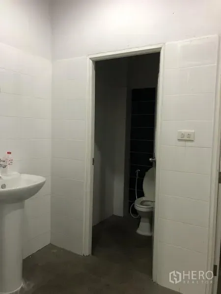 Factory for rent in Samut Prakan - Clean tiled restroom with pedestal sink and toilet.