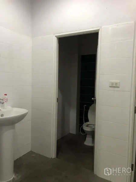 Factory for rent in Samut Prakan - Clean tiled restroom with pedestal sink and toilet.