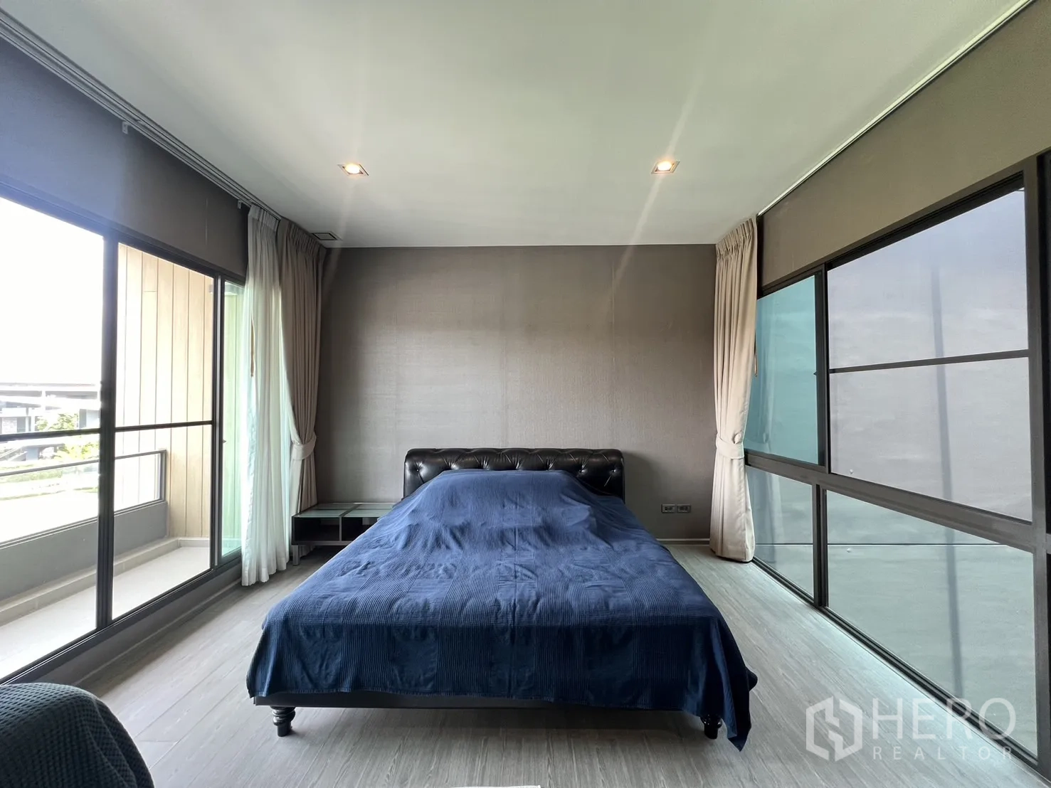 联排别墅 出租在Lat Phrao, Bangkok - 主臥另一角度，兩側大窗與窗簾。