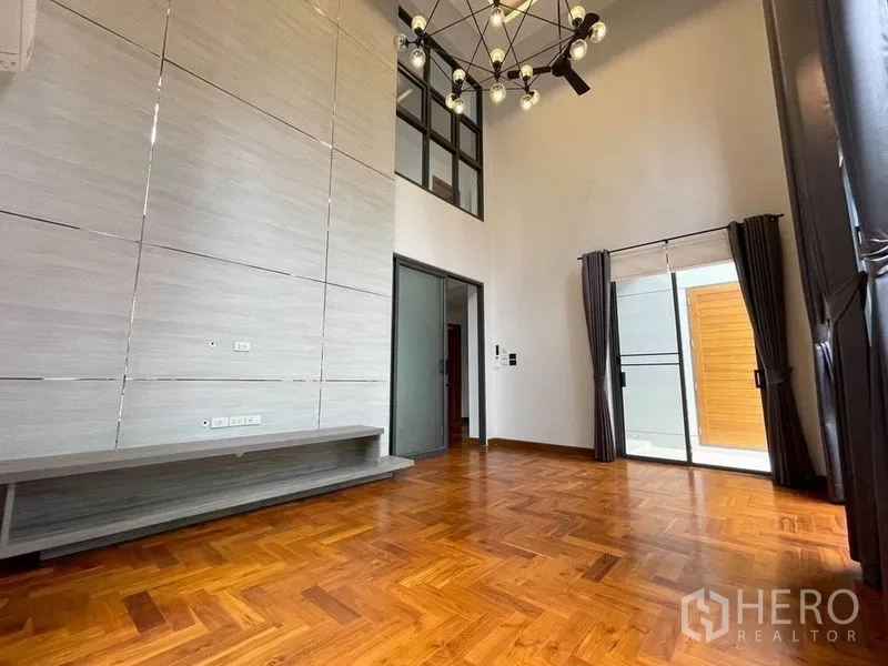 Detached House for rent in Bang Na, Bangkok - Open-plan living and kitchen with island, staircase and garden-facing windows.