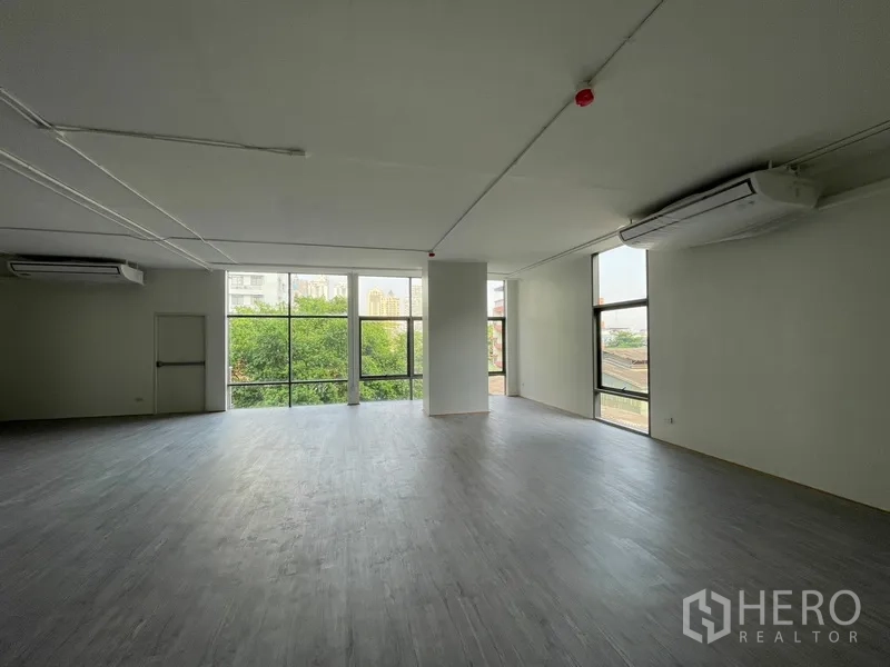 Office Space for rent in Bang Rak, Bangkok - Open-plan 120 sqm office with floor-to-ceiling windows overlooking greenery and city skyline.