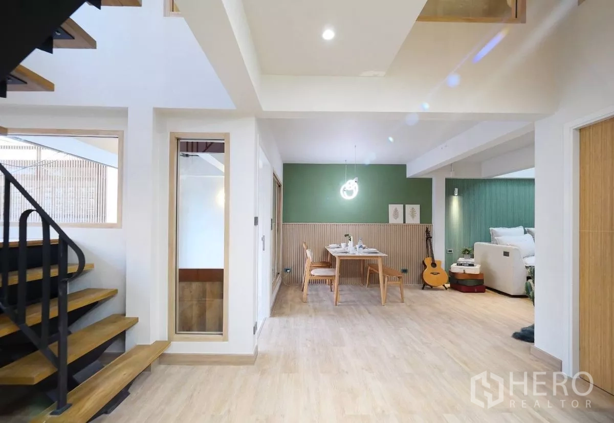 ทาวน์เฮาส์ ให้เช่าในWatthana, Bangkok - พื้นที่โอเพ่นแพลนชั้นล่าง เห็นบันได มุมทานอาหารผนังสีเขียว และมุมพักผ่อน
