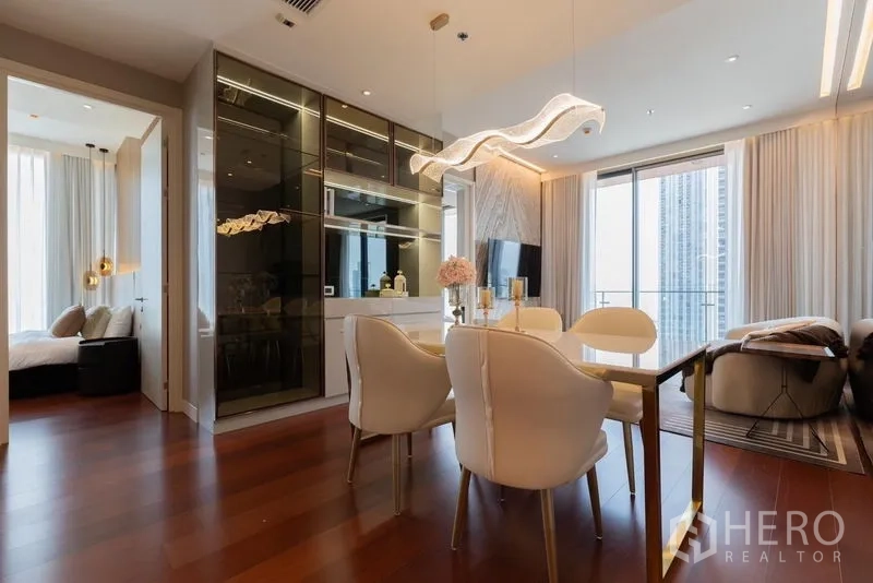 公寓 出租在Watthana, Bangkok - 开放式客餐厅，玻璃柜、设计感照明与通往阳台的推拉门。