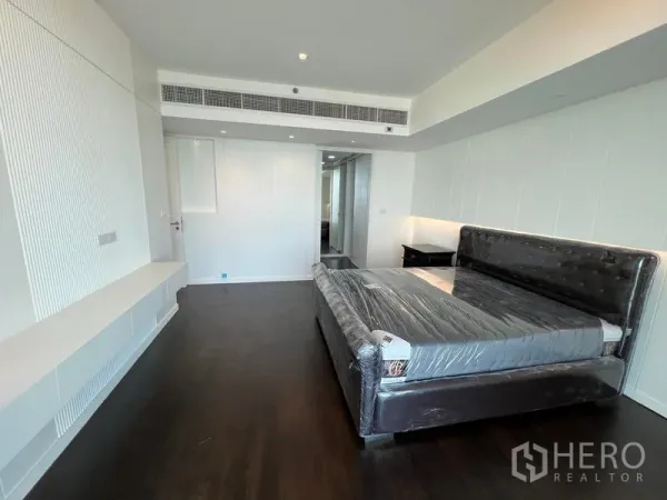 Condominium for rent - Spacious master bedroom with dark wood floors, upholstered bed and built-in media shelf.