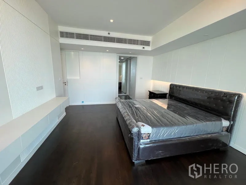 Condominium for rent - Spacious master bedroom with dark wood floors, upholstered bed and built-in media shelf.