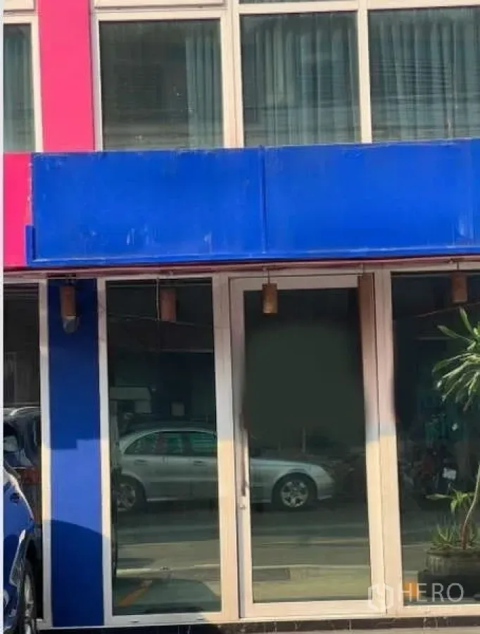 零售空间 出租在Khlong Toei, Bangkok - 一层店面外立面，蓝色招牌与双扇玻璃门，临繁忙小巷。