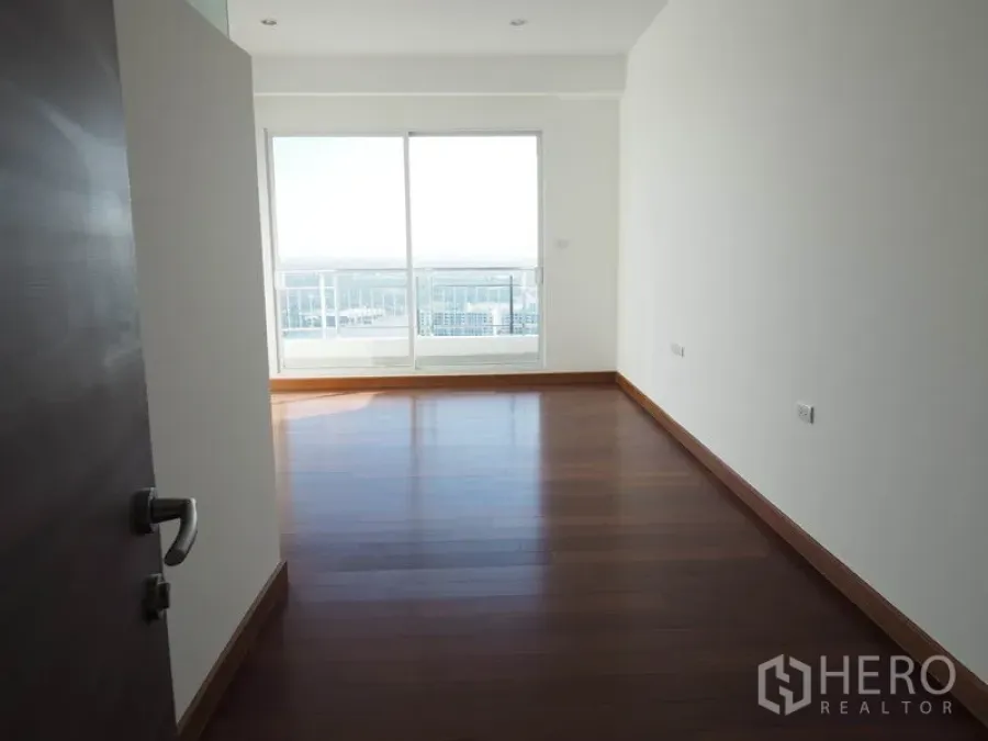 Condominium for rent or sale in Yan Nawa, Bangkok - Sunlit bedroom with wood floors and floor-to-ceiling window to a city balcony.
