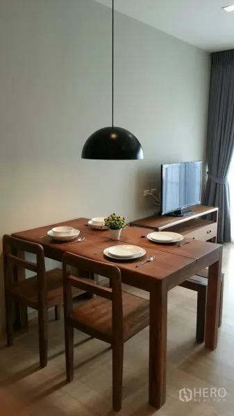 คอนโด ให้เช่าหรือขายในWatthana, Bangkok - โต๊ะทานอาหาร 4 ที่นั่ง ใต้โคมไฟสีดำ ข้างชั้นวางทีวีและผ้าม่านสูงจรดเพดาน