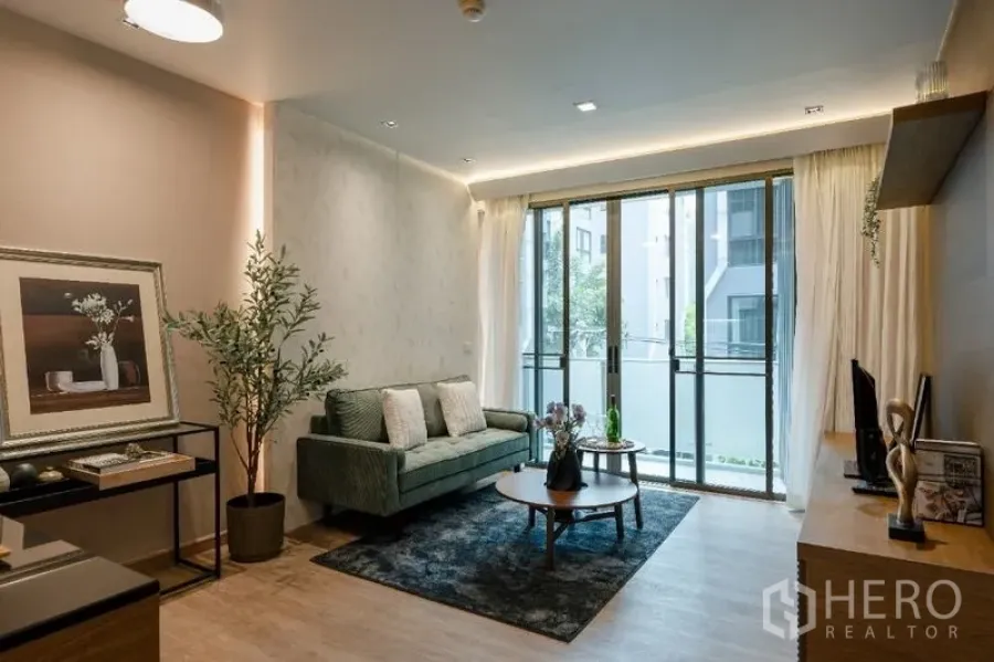 公寓 出售 - 明亮起居区，双茶几、绿色沙发与滑动阳台门。