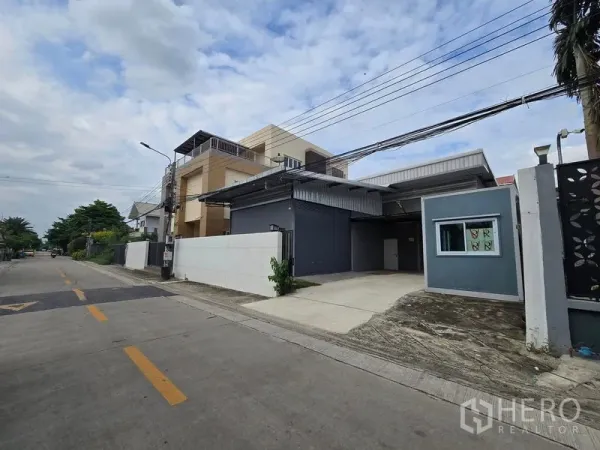 Warehouse for rent in Don Mueang, Bangkok - Angled view showing wide road access and a concrete driveway to the warehouse roller shutter.