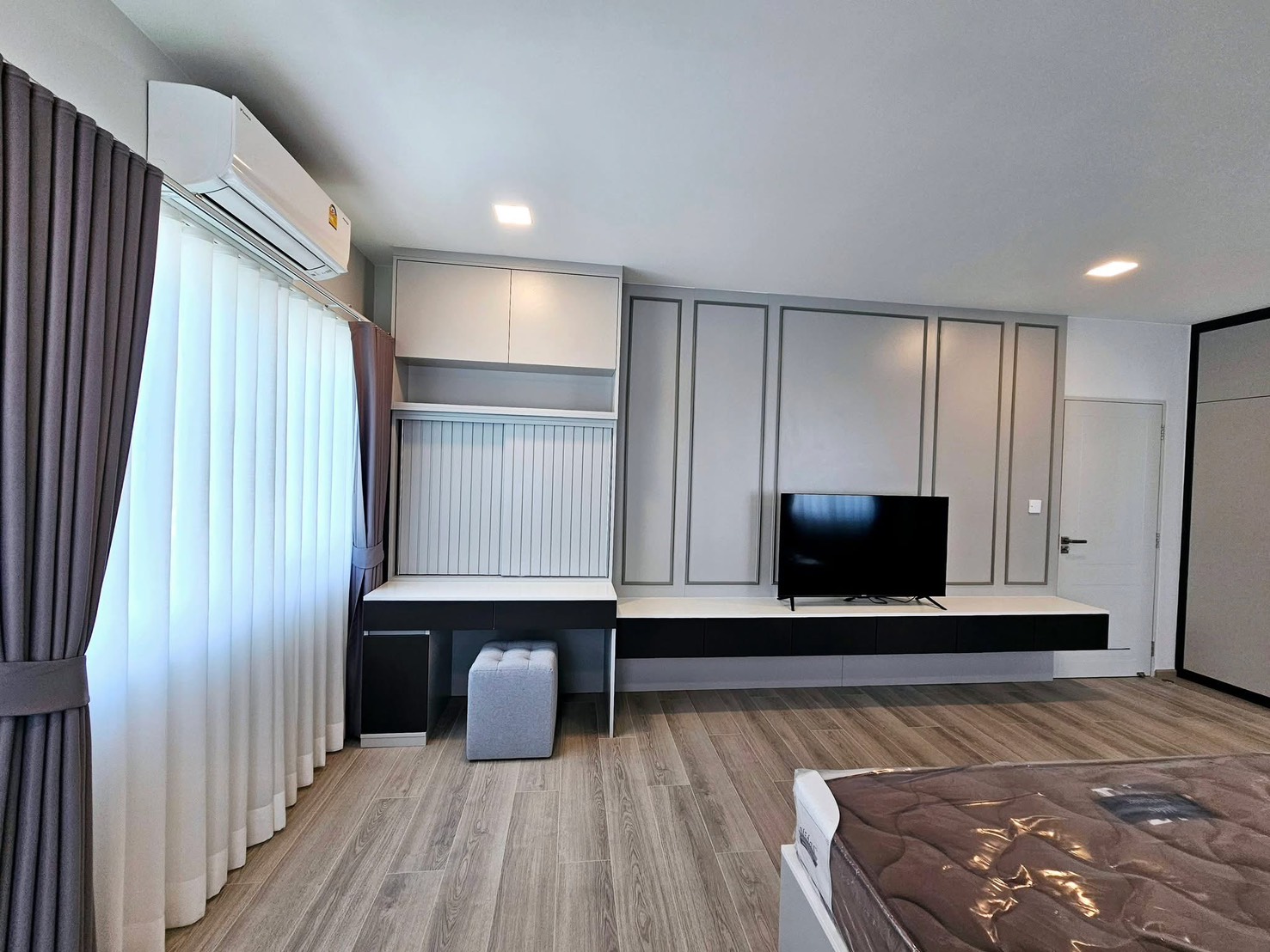 Detached House for rent in Bang Phli, Samut Prakan - Spacious bedroom with TV wall, built-in desk, and floor-to-ceiling curtains.
