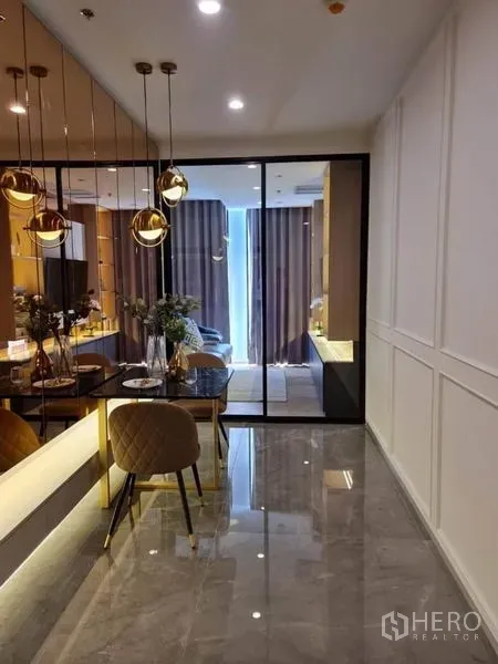 คอนโด ขายในPathum Wan, Bangkok - มุมทานอาหารโคมแขวนสีทอง ผนังกระจกเงา และฉากกั้นกระจกสู่พื้นที่นั่งเล่น