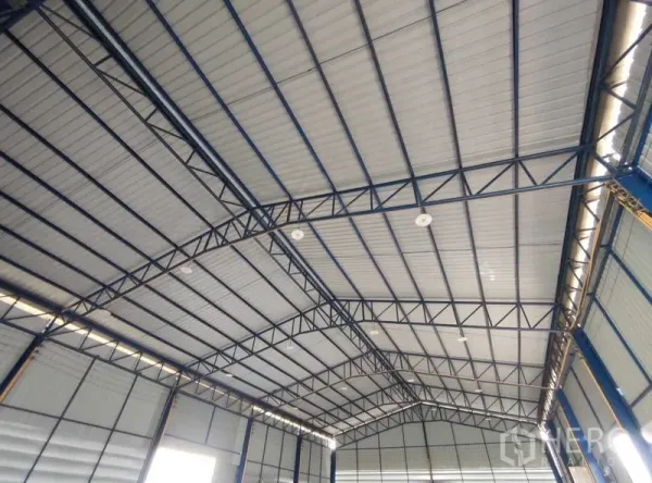 Warehouse for sale in Nakhon Pathom - Interior view of the warehouse’s high arched steel‑truss roof with insulated metal panels and natural light strips.