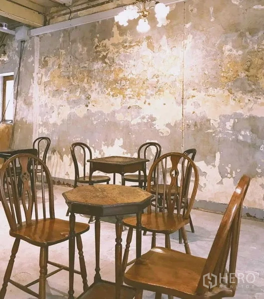 Shophouse for rent in Bang Rak, Bangkok - Seating area with vintage wooden chairs and tables against distressed plaster.