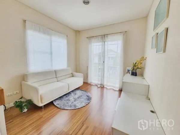 独立式住宅 出租在Prawet, Bangkok - 采光充足的楼上起居室，白色沙发与阳台推拉门，木地板。