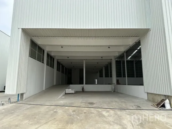 Factory for rent in Pathum Thani - Covered loading bay with a ramp leading into the warehouse interior and high canopy.