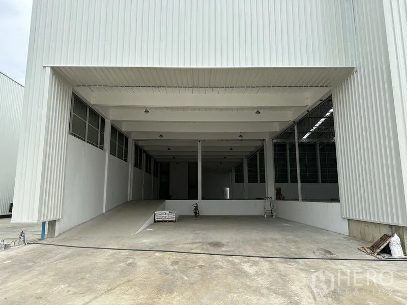 Factory for rent in Pathum Thani - Covered loading bay with a ramp leading into the warehouse interior and high canopy.