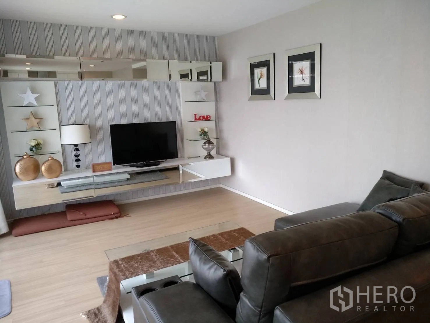 คอนโด ให้เช่าหรือขายในPathum Wan, Bangkok - ห้องนั่งเล่นสว่าง โซฟาหนัง ชุดผนังทีวีลอย ชั้นตกแต่ง และพื้นไม้สีอ่อน