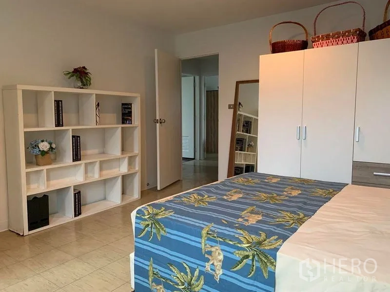 Townhouse for rent in Watthana, Bangkok - Bedroom with blue bedspread, white wardrobe and built-in shelving.