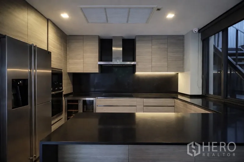Semi-detached House for rent in Watthana, Bangkok - Spacious U-shaped kitchen with built-in appliances and island counter.