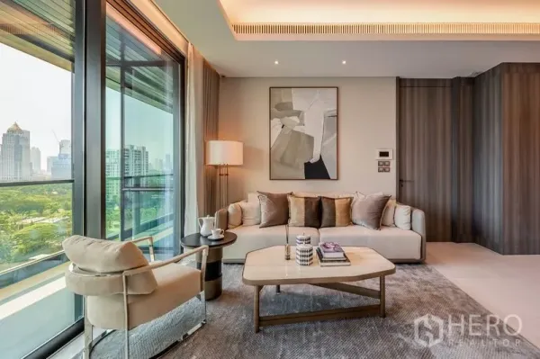 Condominium for rent or sale in Pathum Wan, Bangkok - Bright living room with neutral sofa, abstract art and floor-to-ceiling windows overlooking Bangkok skyline and a green park.