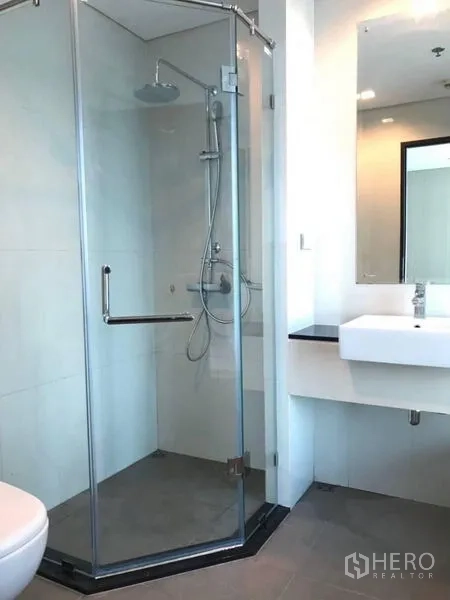 Condominium for rent in Watthana, Bangkok - Modern bathroom with glass shower enclosure and square basin.
