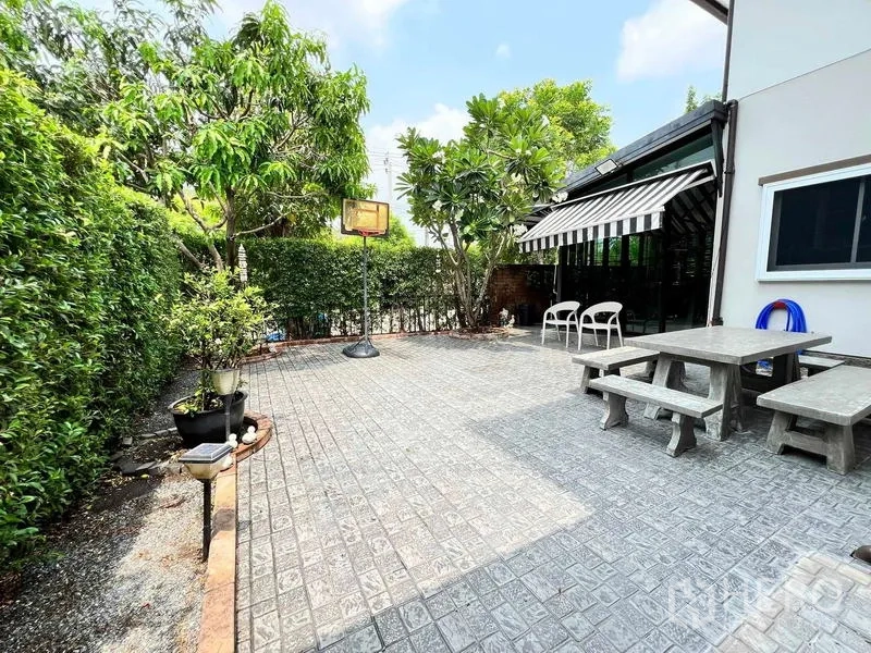 บ้าน ขายในBang Kruai, Nonthaburi - ลานระเบียงปูพื้นกว้าง มีต้นไม้ แนวพุ่มไม้ กันสาดลายทาง และชุดนั่งเล่นกลางแจ้ง
