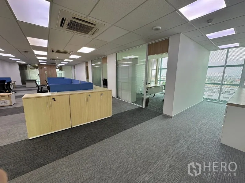 Office Space for rent - Open-plan office area with blue dividers, glass meeting rooms and natural light at the far end.