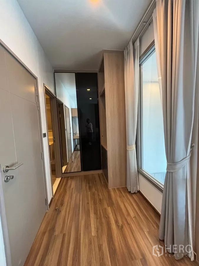Condominium for rent or sale in Watthana, Bangkok - Bright hallway with wardrobes, full-height window and curtains.