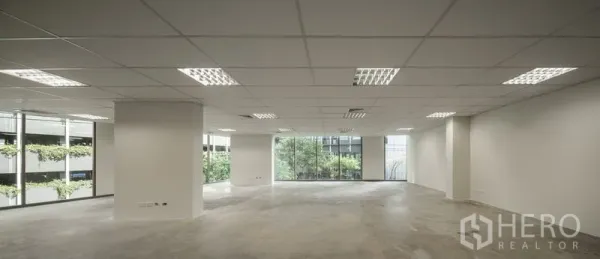 Office Space for rent in Bang Kapi, Bangkok - Open office space with big windows facing greenery and a neighboring building.