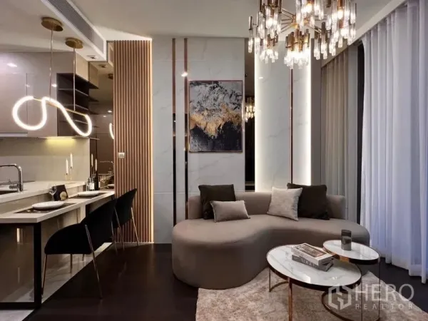 Condominium for rent in Watthana, Bangkok - Contemporary living room with curved sofa, marble accent wall, and illuminated breakfast bar lighting.