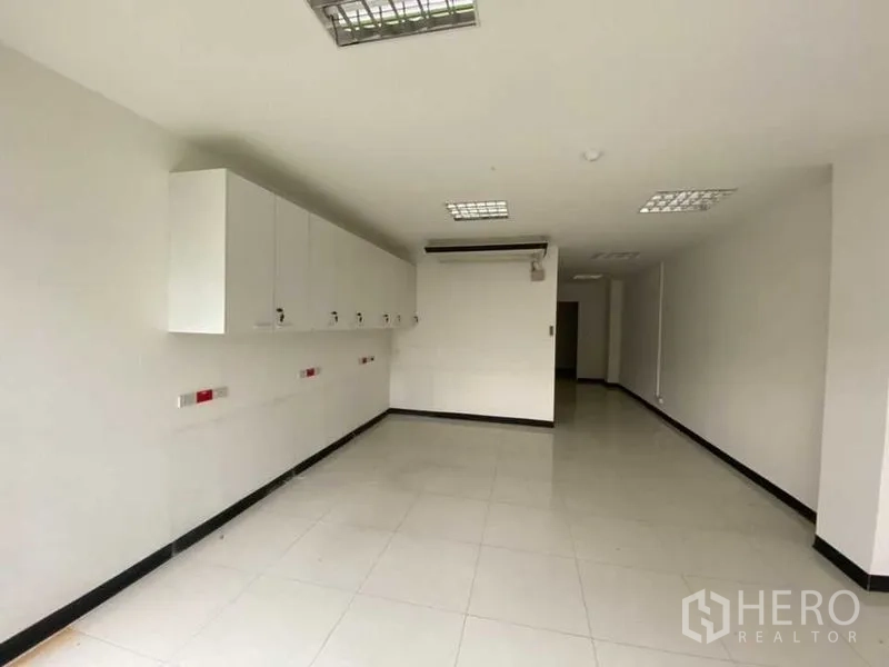 零售空间 出租 - 狭长工作区，壁柜、明亮瓷砖与网格灯。