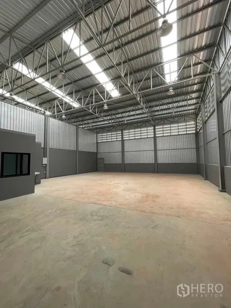 Warehouse for rent in Phra Samut Chedi, Samut Prakan - Spacious warehouse interior showing a 6‑meter steel‑truss roof with skylights and a reinforced concrete floor.
