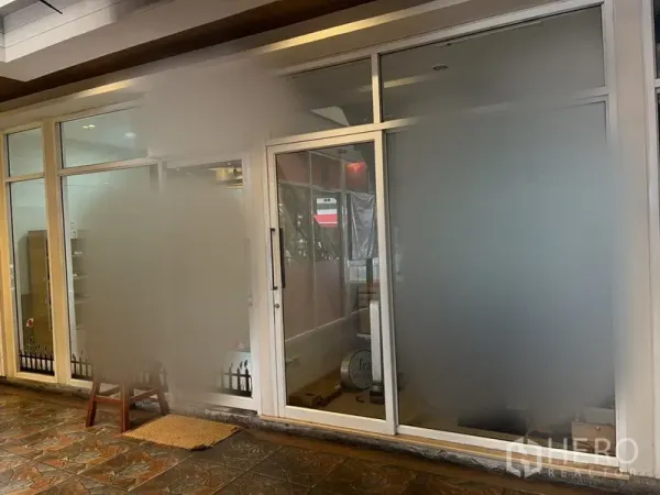 零售空间 出租在Khlong Toei, Bangkok - 零售铺外立面，大幅磨砂玻璃与推拉入口门，吊顶射灯与石质地砖。