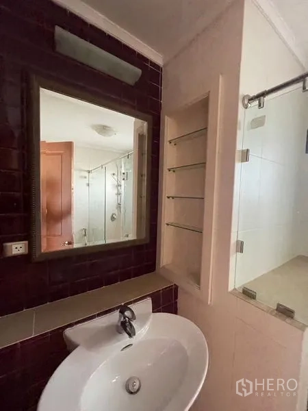 Condominium for rent in Watthana, Bangkok - Bathroom with vanity mirror and glass-enclosed shower.