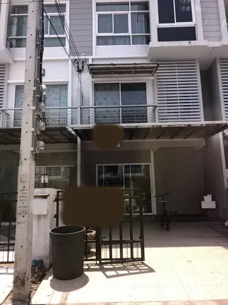 Townhouse for sale in Suan Luang, Bangkok - Three-storey modern townhouse exterior in Prawet, Bangkok with gated carport, metal awning, balcony and sliding glass doors.