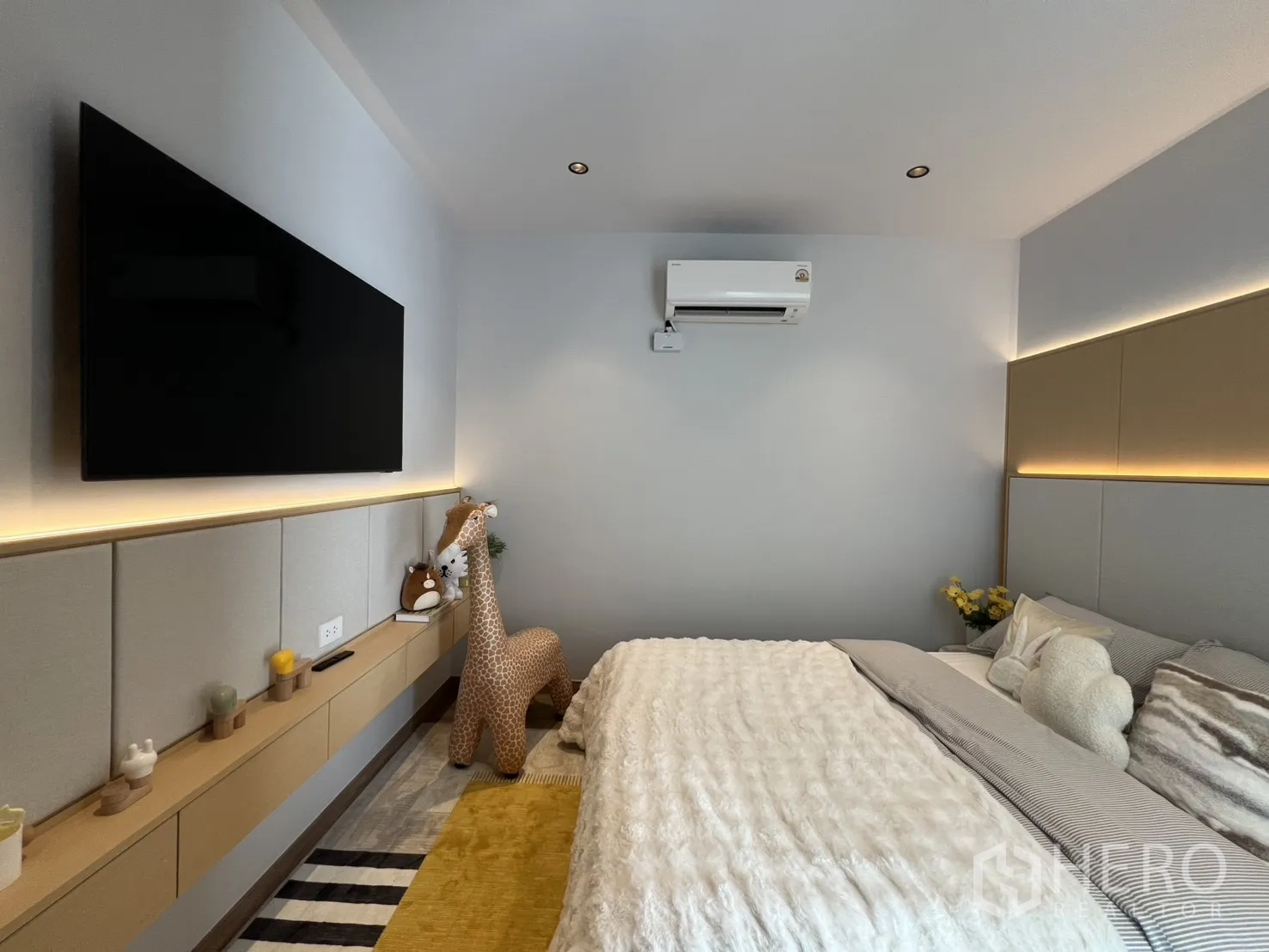 Townhouse for rent in Mueang Samut Prakan, Samut Prakan - Cozy bedroom with padded headboard lighting, wall-mounted TV, and air conditioner.