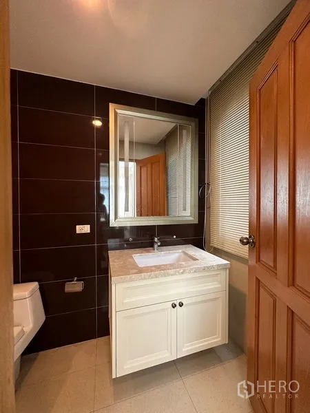 Detached House for rent or sale in Pak Kret, Nonthaburi - Powder room with marble vanity and dark tiled feature wall.