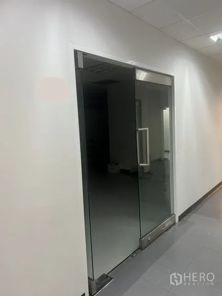 办公空间 出租 - 白色走廊中的玻璃门办公室入口，灰色地砖。