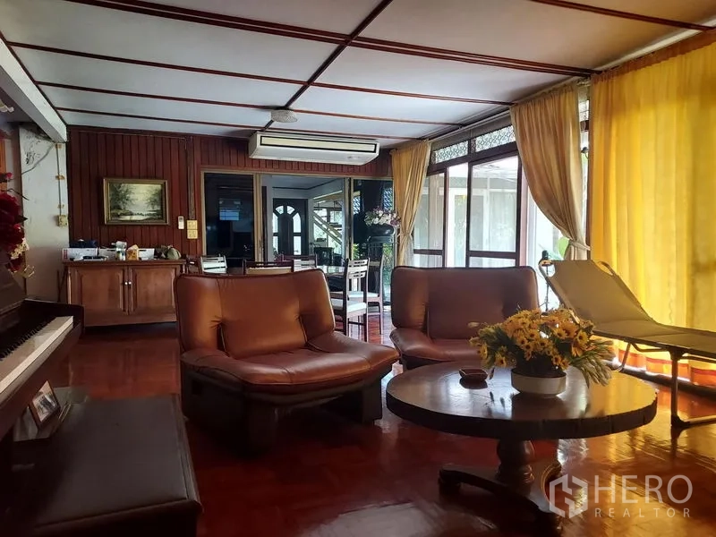 บ้าน ให้เช่าในMueang Samut Prakan, Samut Prakan - ห้องพักผ่อนพร้อมเก้าอี้หนัง เปียโน และผ้าม่านสูงจรดพื้น