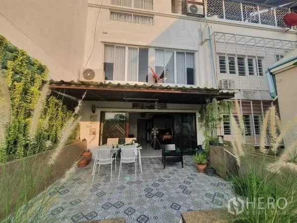 Townhouse for rent or sale in Bang Kho Laem, Bangkok - Rear exterior view of the townhouse with tiled outdoor area and greenery.