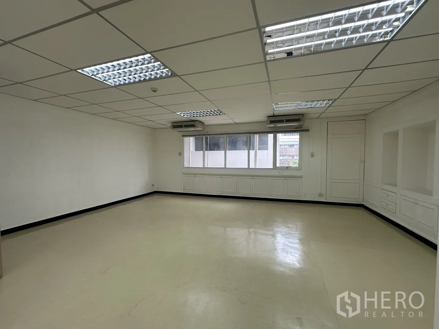 ออฟฟิศ for rent in Pathum Wan, Bangkok - ออฟฟิศโอเพนสเปซสว่าง ฝ้าทีบาร์ ไฟฟลูออเรสเซนต์ หน้าต่างยาว และตู้บิลต์อินตามผนัง.