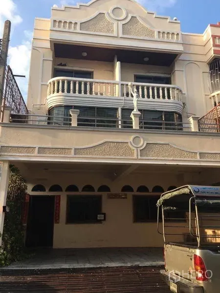 带办公室的家 出租在Bang Na, Bangkok - 三层米色外立面的家庭办公楼，带遮蔽车位与弧形阳台，位于邦那街景。