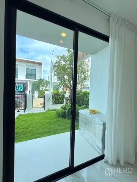 Detached House for rent in Samut Prakan - View from the living room through sliding glass doors to the front lawn and porch.