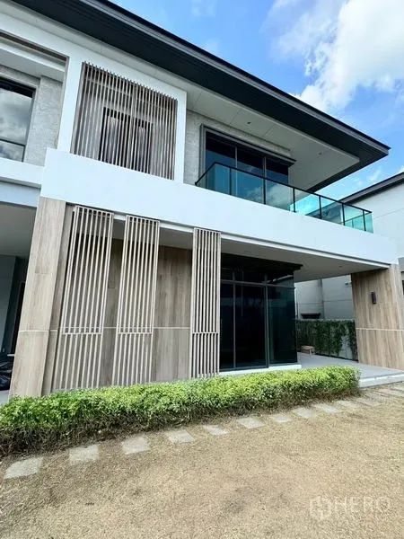 Detached House for rent or sale - Another view of the modern facade with glass balcony and vertical slats beside the lawn.