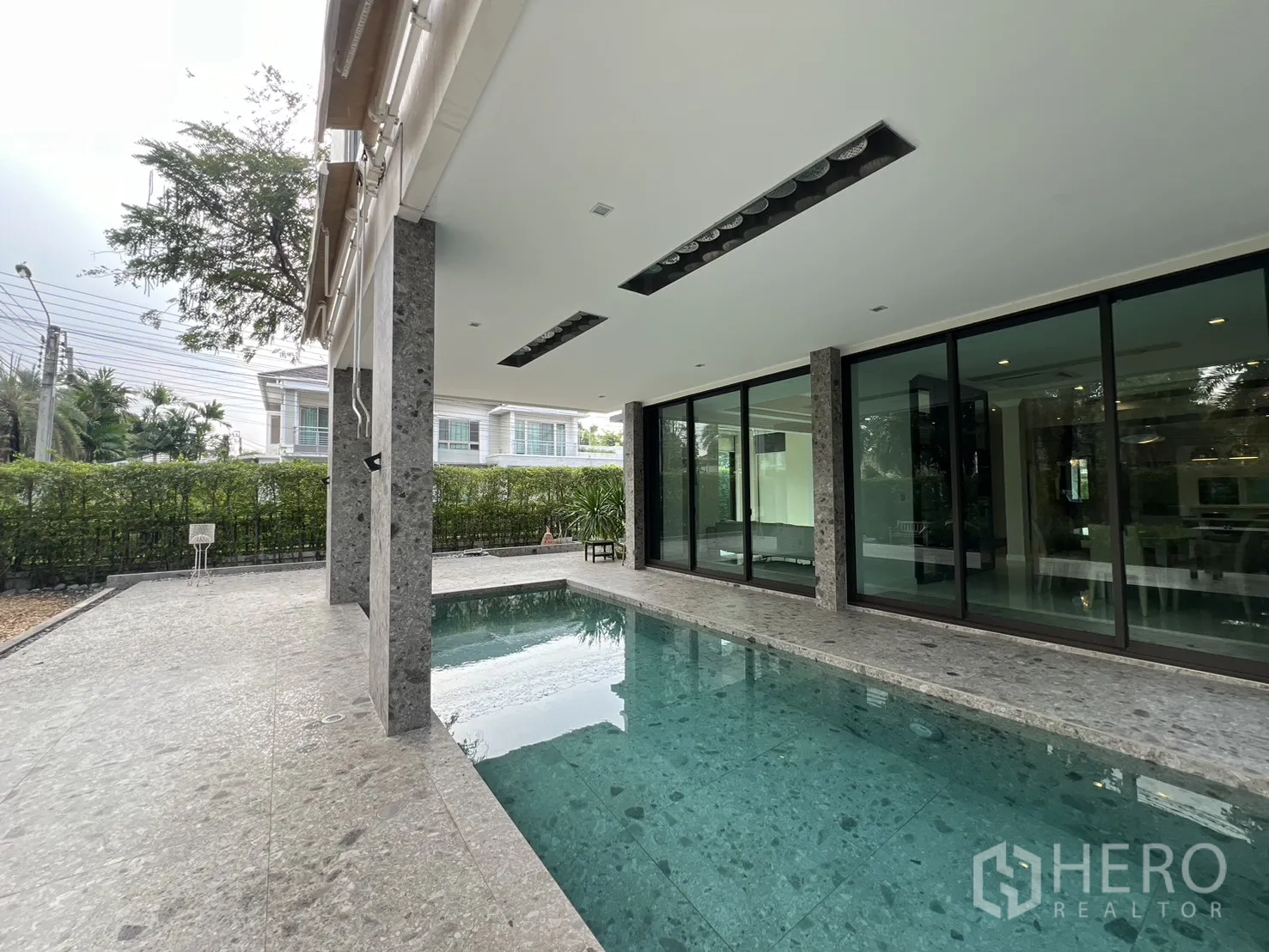 独栋房屋 for rent in Prawet, Bangkok - 泳池露台在遮阳棚下，滑动玻璃门连接室内外。