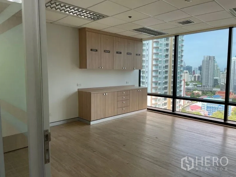 Office Space for rent - Private room with built-in wood pantry cabinets and full-height windows offering a city view.