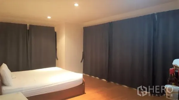 Condominium for rent in Watthana, Bangkok - Spacious bedroom with a double bed, recessed ceiling lights, wooden floor and blackout curtains.